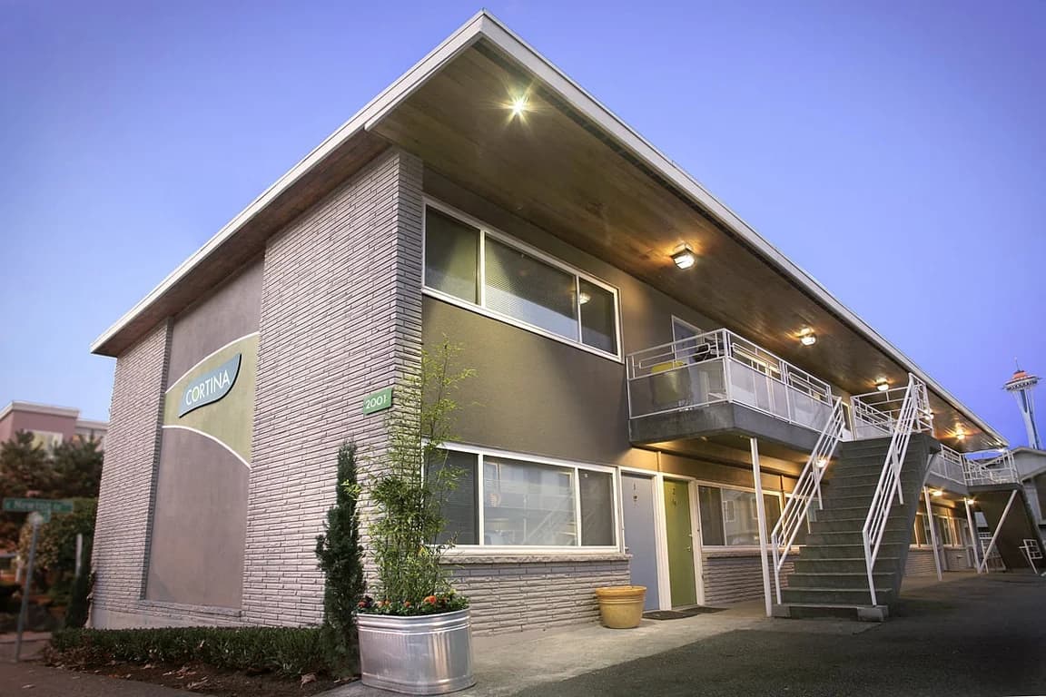 Exterior of Cortina Apartments building in Seattle with grey brick, stucco, stairs, balconies, an...